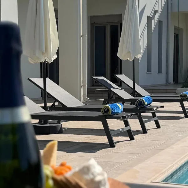 Image depicting sunbeds with towels and a bottle of wine in the foreground