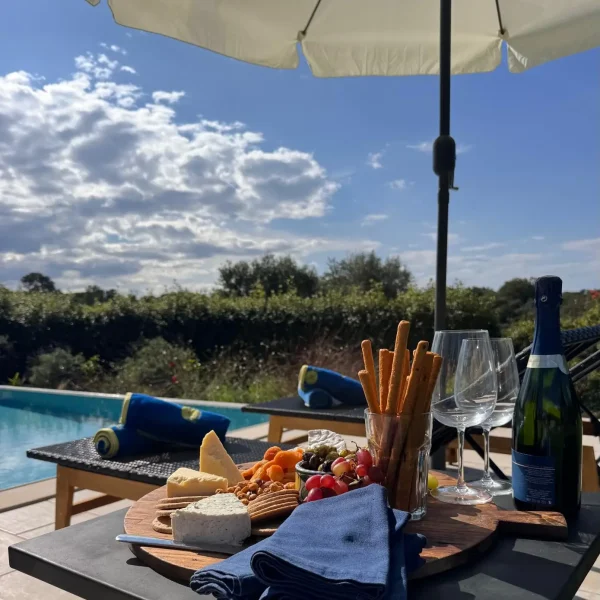 Image depicting sunbeds with a cheeseboard and bottle of wine betweeen